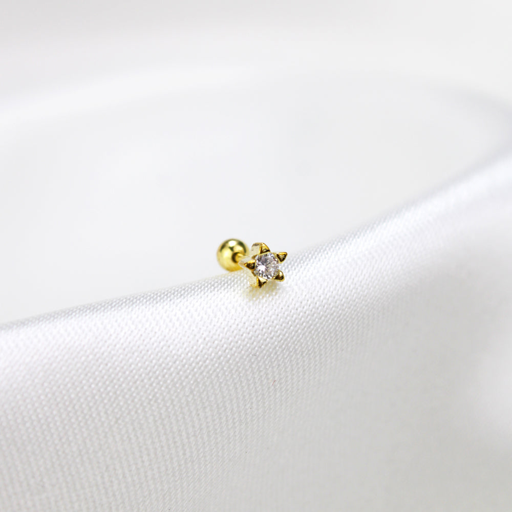 Piercing en forma de estrella dorada con piedra al centro 