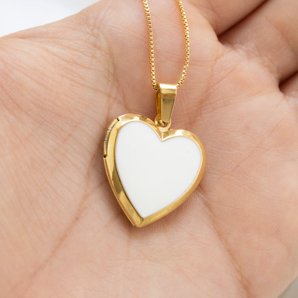 Collar relicario en forma de corazón con interior blanco, para colocar fotos dentro de el. Collar en tono dorado/acero