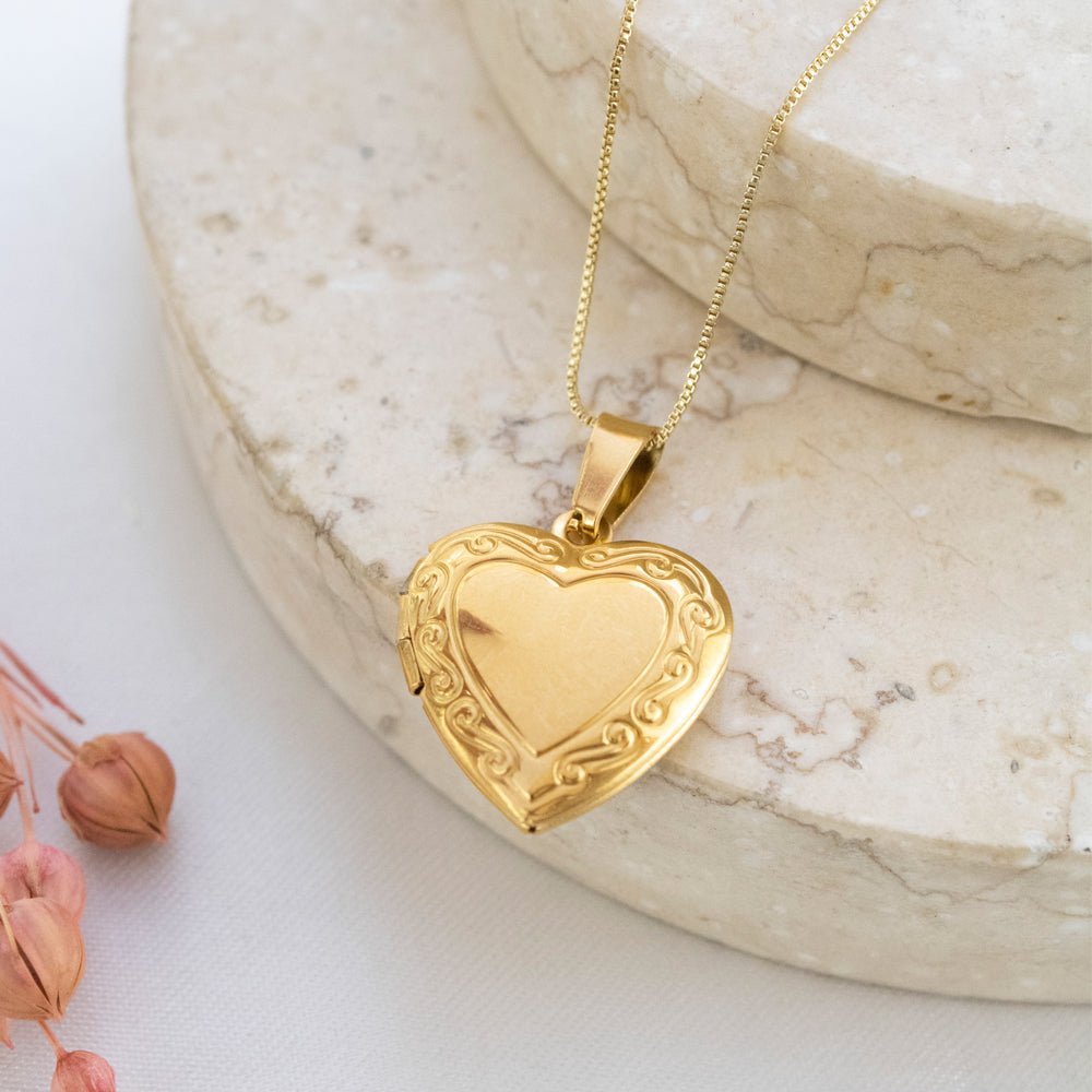 Collar relicario en forma de corazón con grabado, para colocar fotos dentro de el. Collar en tono dorado/acero