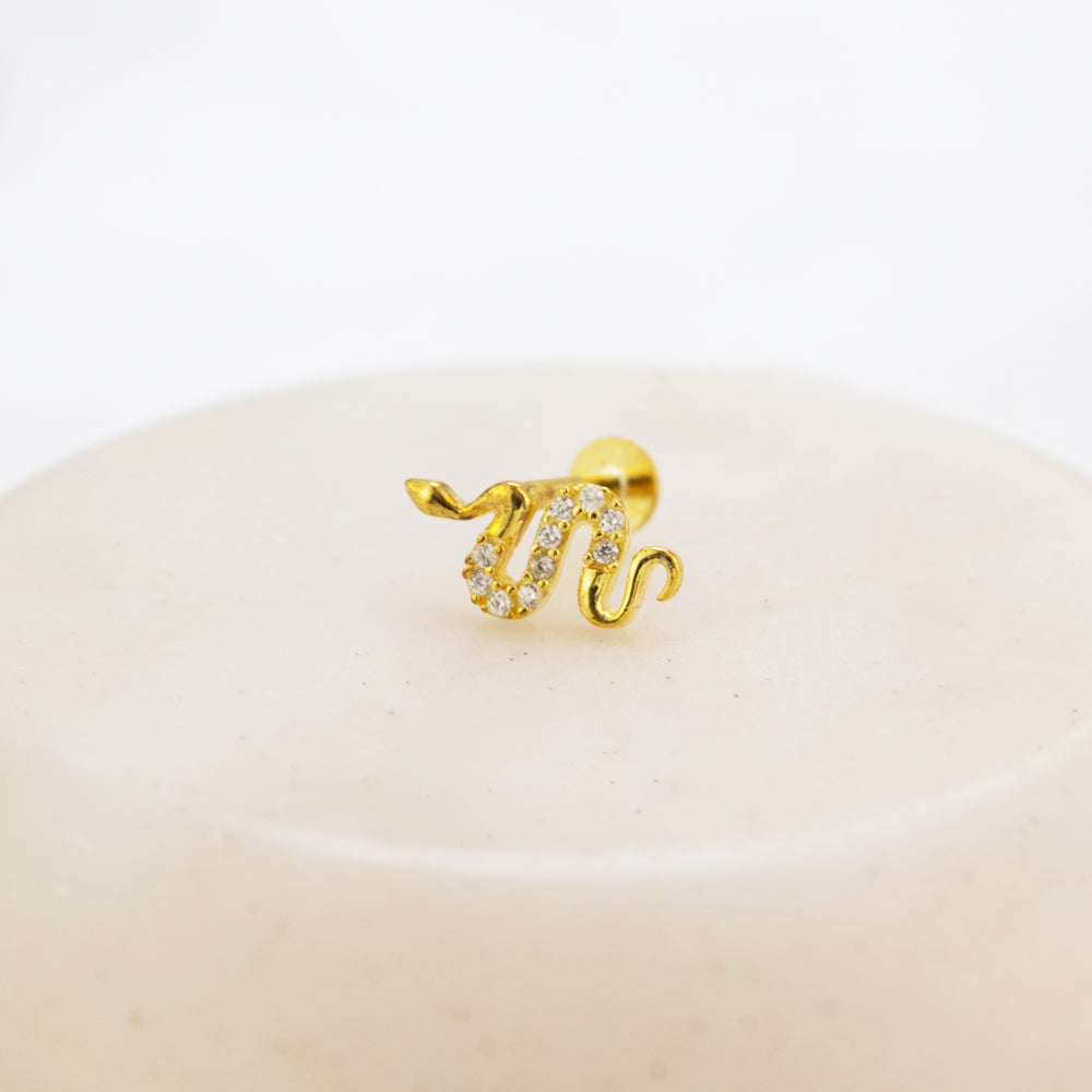 Piercing en forma de serpiente dorada con piedras en el centro